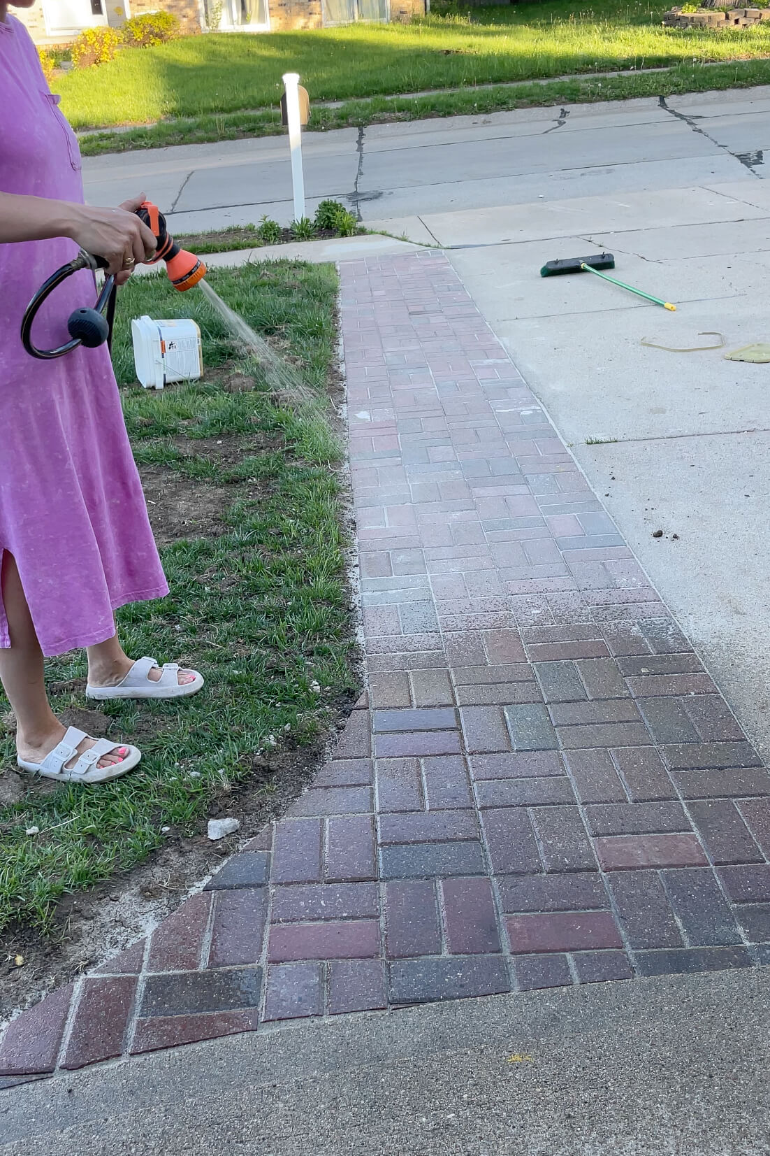 Spraying water on polymer sand so that it hardens around pavers.